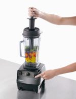Using the Vita-Prep 3 tamper to press ingredients onto the blades