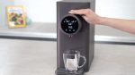 Hand selecting hot water on the DNA Water Purifier 2 as it fills a mug