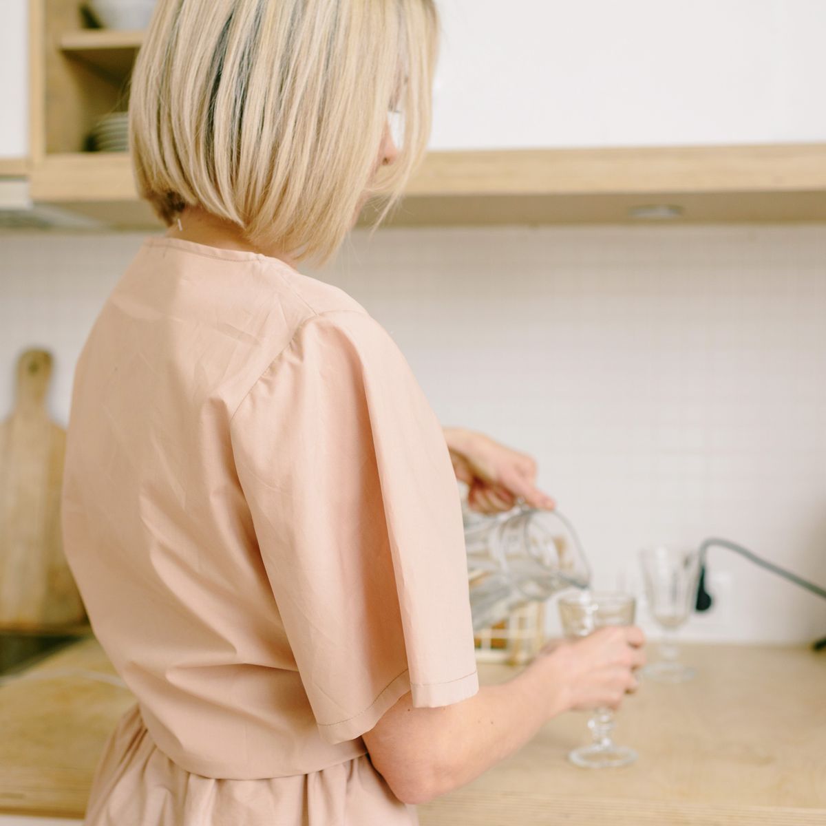 A woman pouring a glass of water in a modern kitchen