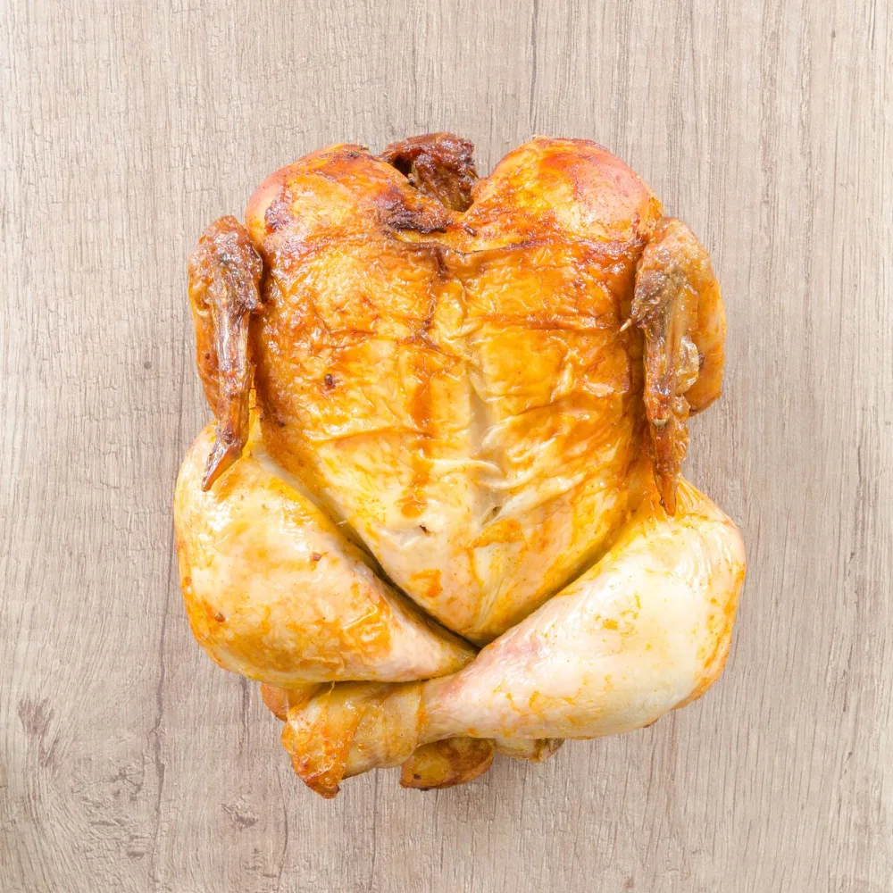 A golden roast chicken on a wooden board