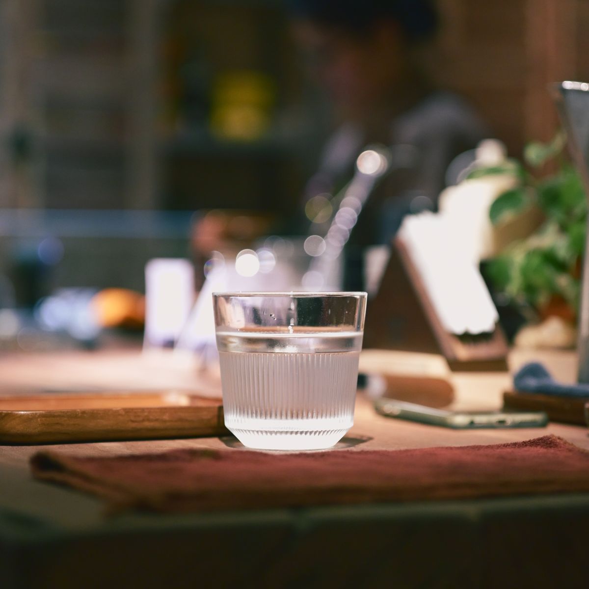 A glass of clear filtered water standing on a wooden kitchen counter