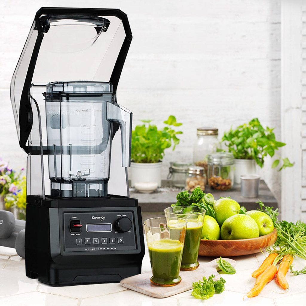 Kuvings CB850 commercial blender on a counter with fresh juice and produce