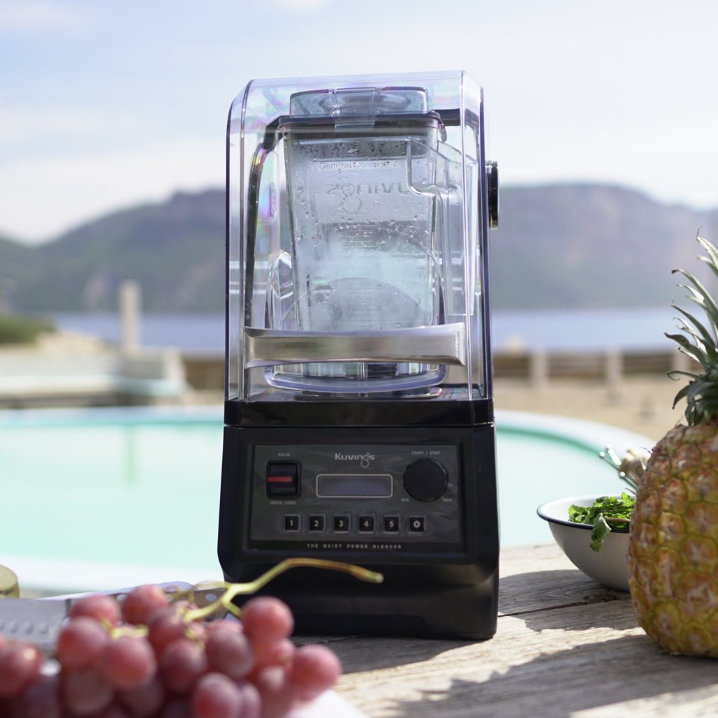 Kuvings CB850 on a poolside bar counter with grapes and pineapple