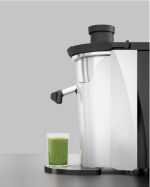 The Zumex Multifruit on a service counter beside a glass of fresh green juice