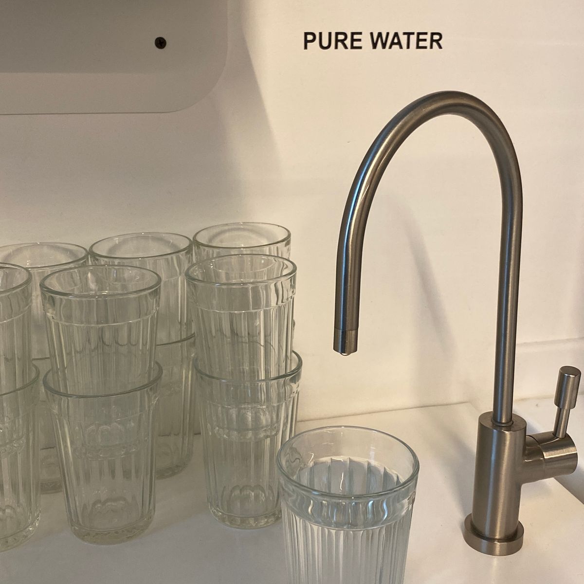 Clean drinking glasses standing beside a kitchen faucet