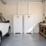 Huawei Power-M 10kW 30kWh system on a garage back wall beside a parked car